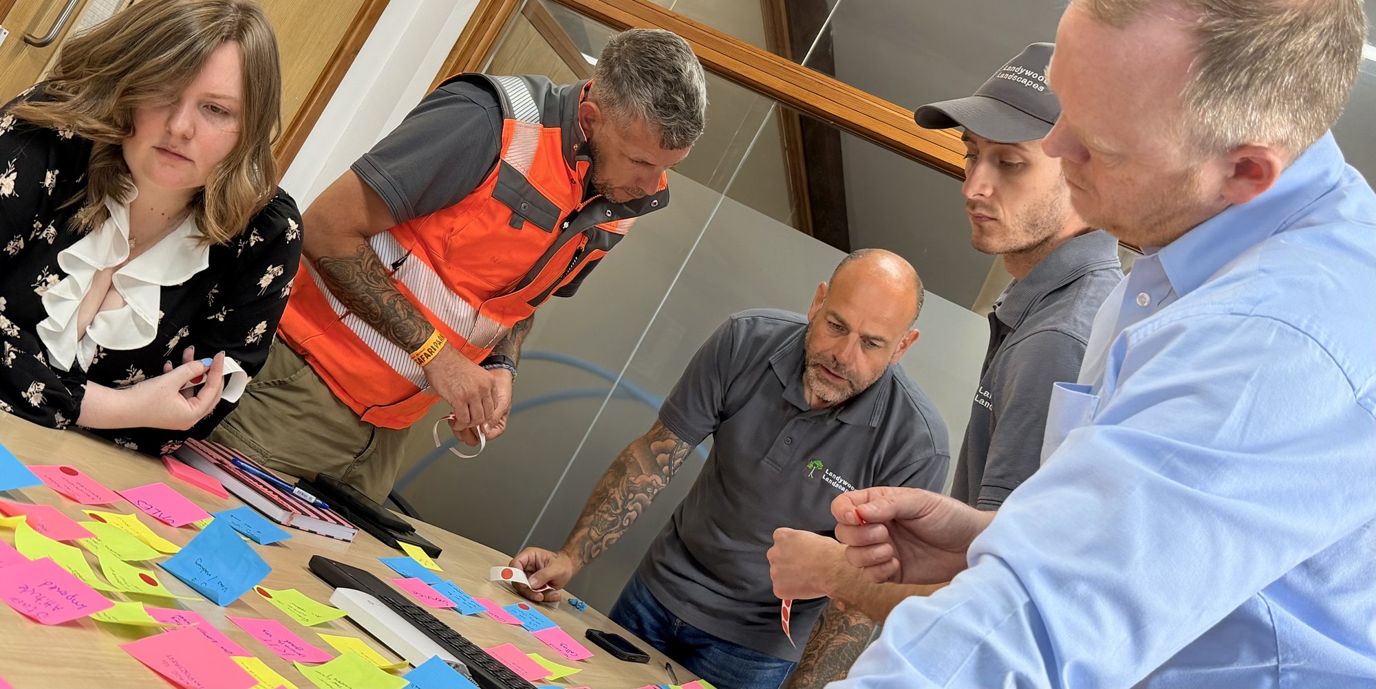 A mixed team working together around a table covered with colour-coded notes